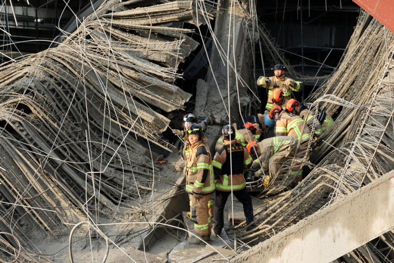 South Korean firefighters inspect rubble at the Gwangju library collapse site, surrounded by tangled rebar and shattered concrete amid steel structures, following an accident that killed four workers.