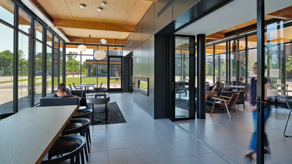 Bright lounge with wooden ceiling and floor-to-ceiling windows facing greenery.