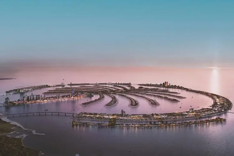 Aerial view of Jebel Ali at dusk, showing its circular layout with 16 fronds, waterfront development, and the central spine where the Friday Mosque will be located.