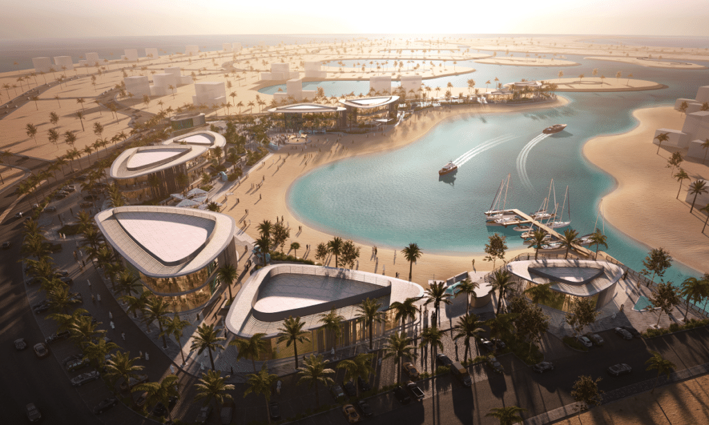 Waterfront commercial area with triangular-roofed modern buildings, a sandy beach, a small marina with sailboats, and pedestrians at Dana Bay.