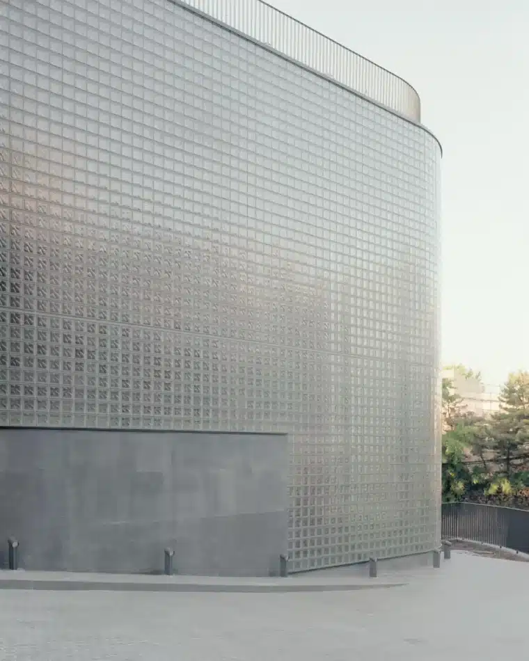 Close-up of grid-patterned glass block wall diffusing daylight on curved facade