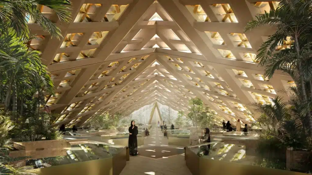 فناء داخلي مضاء بالشمس مع سقف شبكي هندسي، محاط بنباتات استوائية وبرك عاكسة، يسير فيه الزوار على طرق مرصوفة.