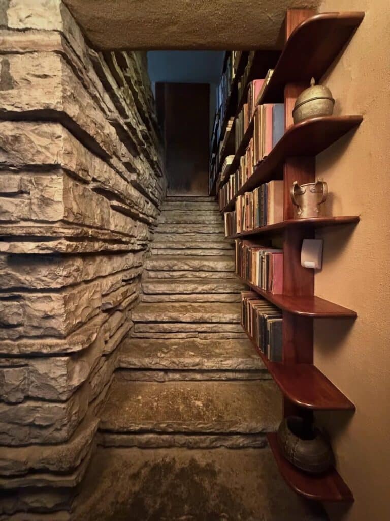 Narrow stone stairwell lined with custom wooden bookshelves inside  .