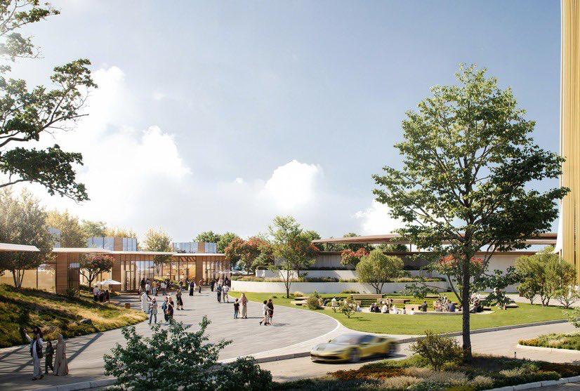 Rendering of Ajdan Island&rsquo;s waterfront promenade in Khobar, showing landscaped green areas, pedestrian pathways, low-rise commercial buildings, and a moving car under a clear sky.