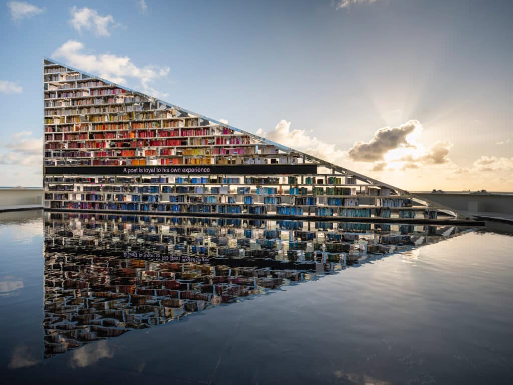 الرفوف الزجاجية والمعدنية تحمل آلاف المجلدات، تنعكس بوضوح فوق حوض الماء العميق والهادئ.