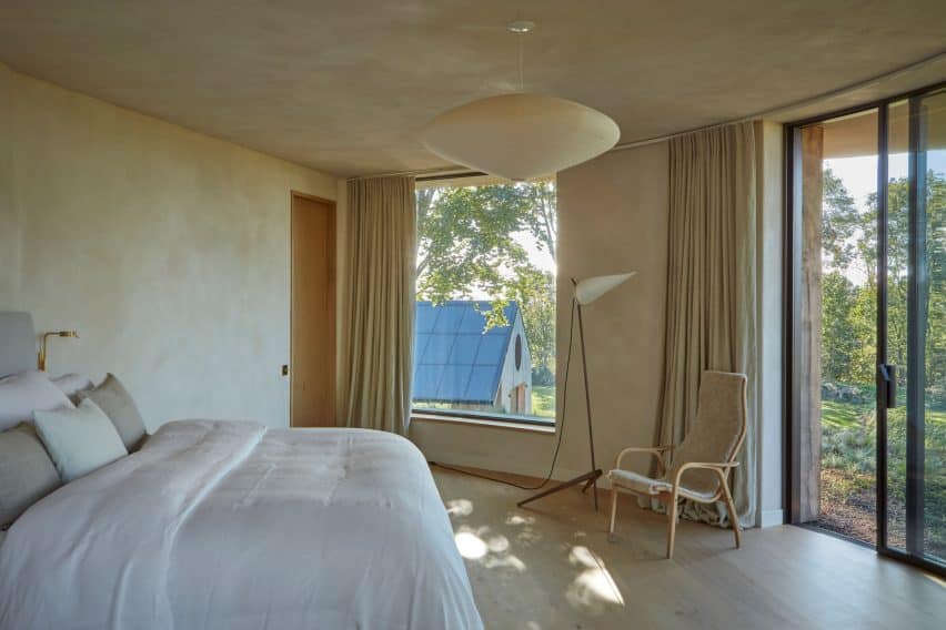 Serene bedroom overlooking the solar-paneled annex roof; clay plaster creates a subtle, tactile finish.