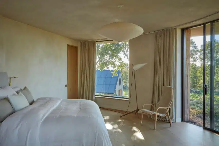Serene bedroom overlooking the solar-paneled annex roof; clay plaster creates a subtle, tactile finish.