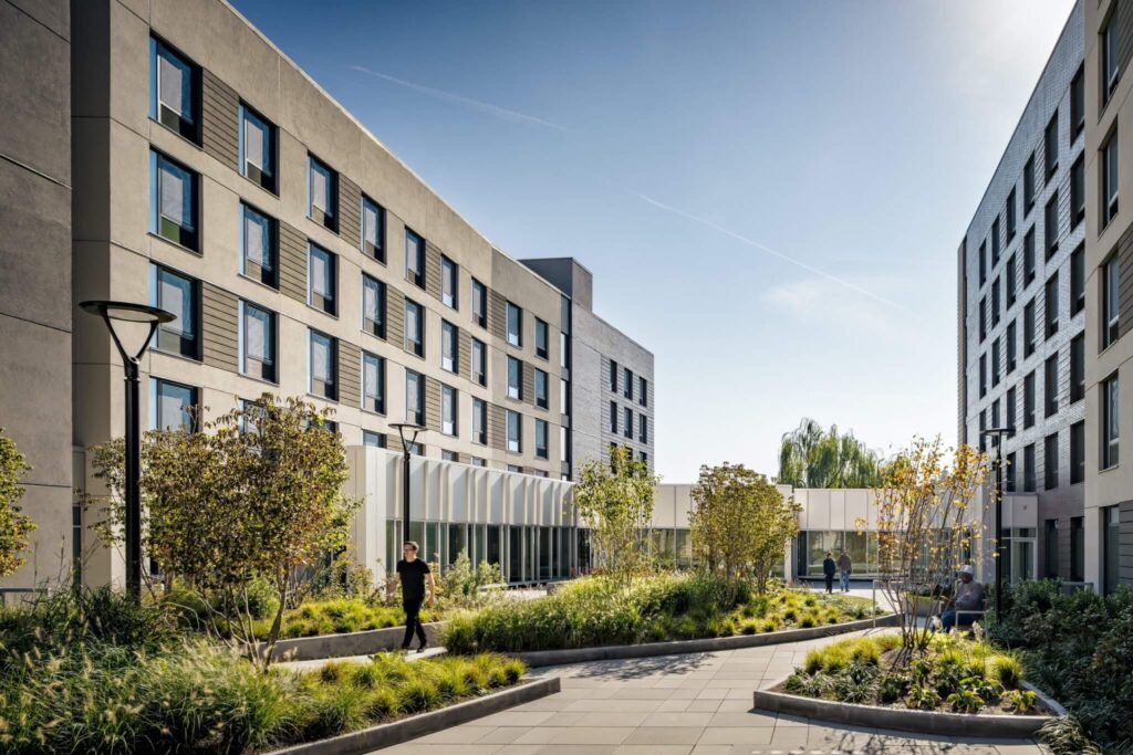 Spacious ground level interior courtyard surrounded by residential blocks, featuring dense landscaping and paved pathways, a core element of the Vertical Integration of Industry and Housing.