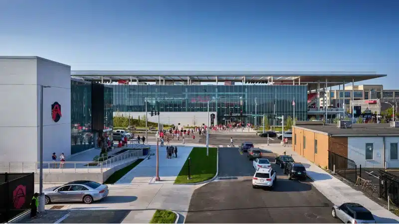 The stadium's transparent glass facade opens onto the street, allowing light to pass and reflecting the city's movement.