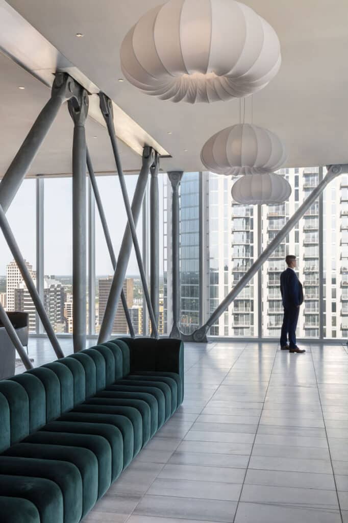 داخلية برج عالي معاصر مع لمبات شمعية نحتية وأعمدة إنشائية مكشوفة، تُظهر تصميمًا سكنيًا فاخرًا في سياق أفق حضري.