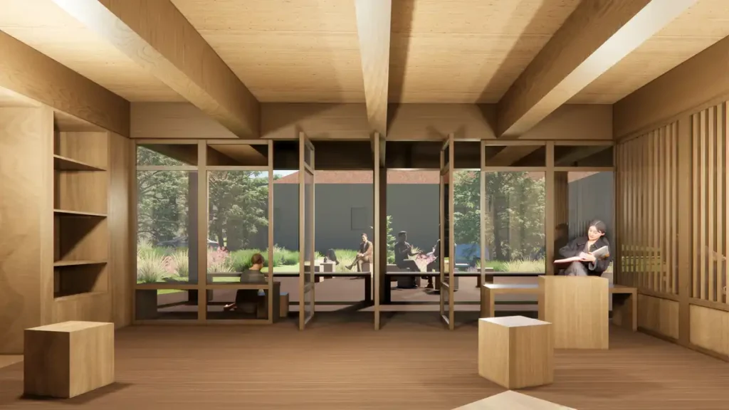 تصور للداخلية المُجدّدة لمكتبة دير بلَم فيليج ضمن مشروعه المعماري في دوردوني، فرنسا، يظهر رفوفًا خشبية ومقاعد مودولارية ونوافذ كبيرة تطل على الخضرة.