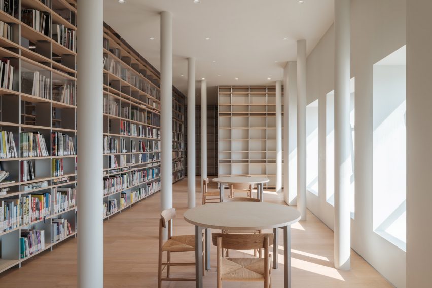 reading area with wooden bookshelves, round tables, and white structural columns within Shanghai&rsquo;s Power Station of Art.