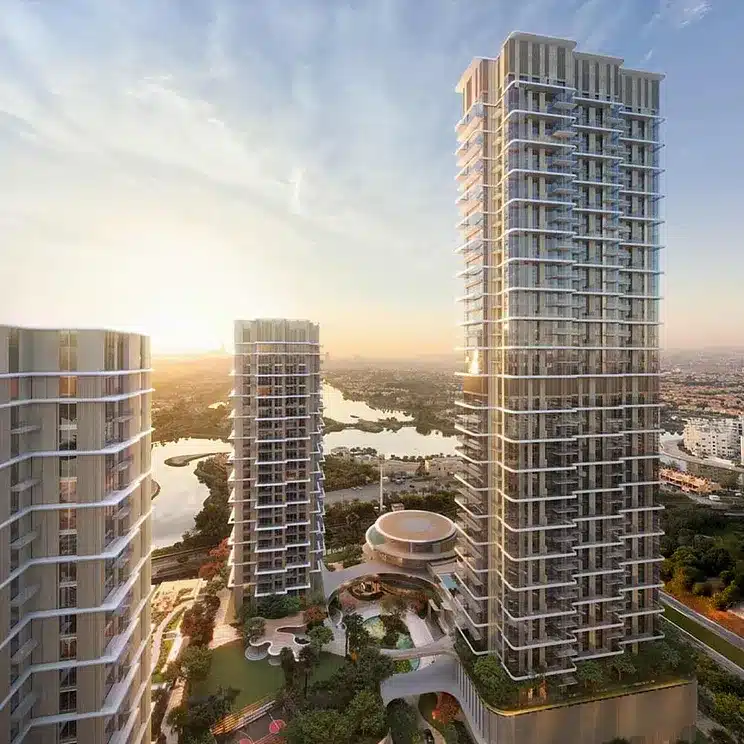 تصوير جوي لمنطقة سيرينيا في جزر جميرا، دبي، يُظهر ثلاثة أبراج شاهقة بشرفات متدلية تطل على ممر مائي وأراضٍ مزروعة عند غروب الشمس. ويتضح تصاميم المعمارية