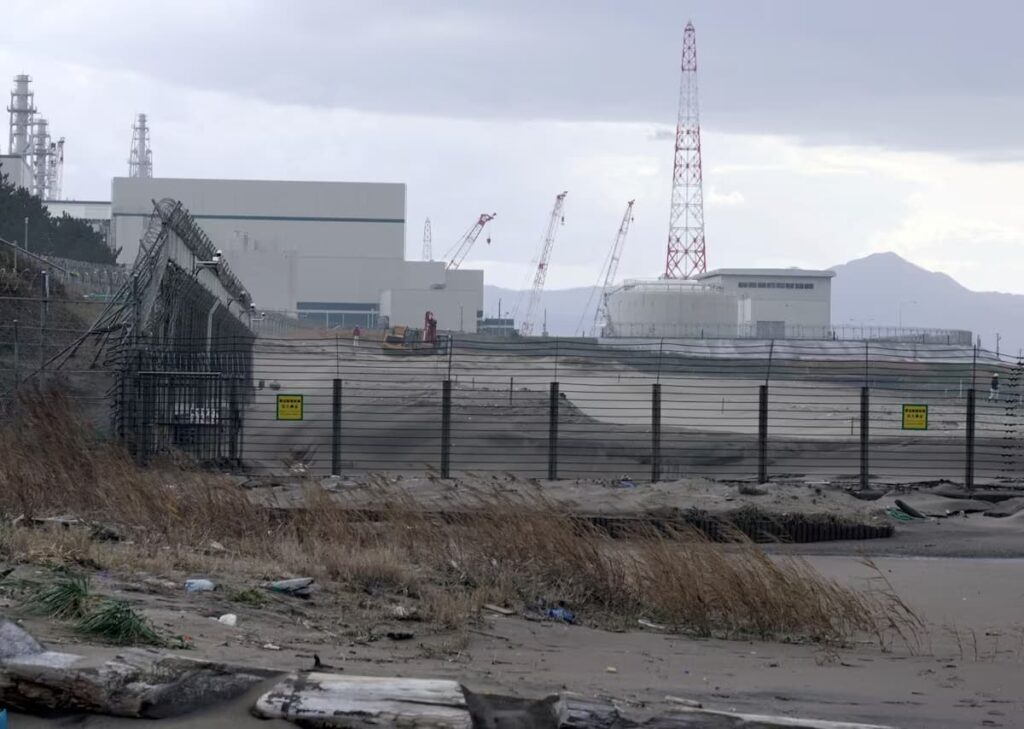 Ground-level view of high security fencing, construction cranes, and service roads at the perimeter of Kashiwazaki-Kariwa Plant.
