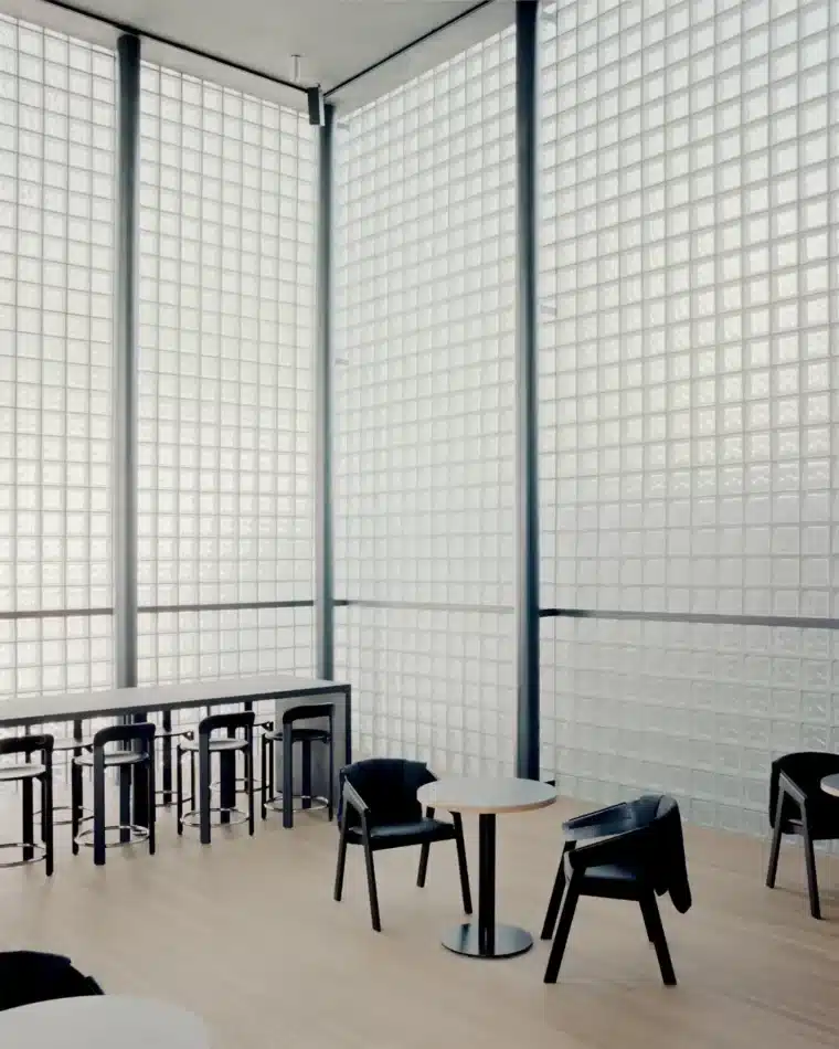 مساحة داخلية بسيطة بجدران من الكتل الزجاجية الشفافة وأثاث أسود في متجر وويماند لعلامة وويونغمي في سيول.