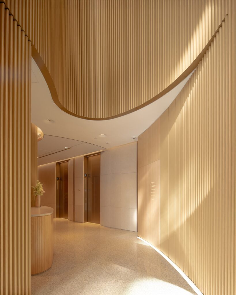 Luxurious interior corridor of a modern office tower, featuring curved wooden walls, polished flooring, and integrated lighting creating a serene ambiance.