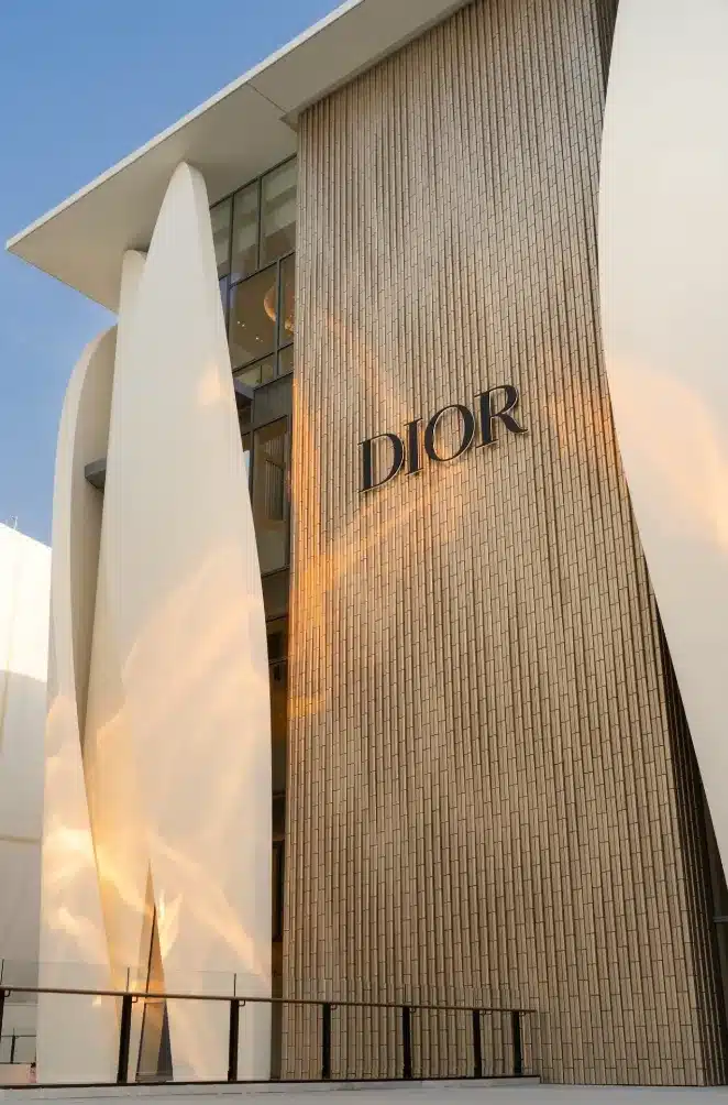 Close-up of a luxury store facade in Beijing showing golden tiles, a “DIOR” logo, and adjacent white curved panels.