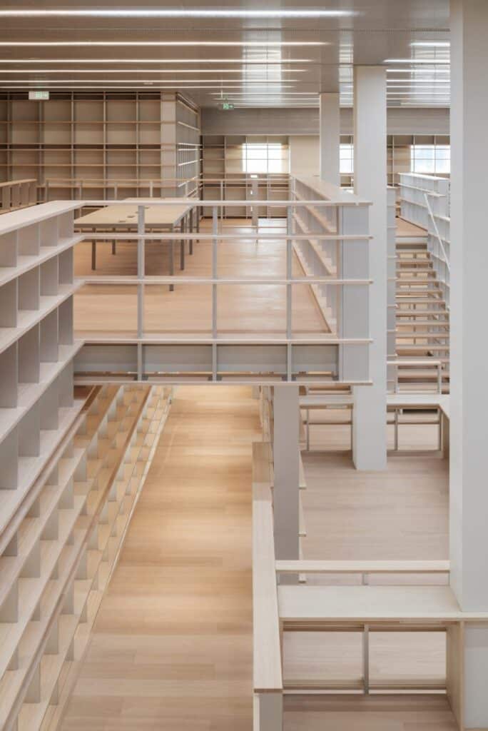 multi level library interior with integrated shelving, walkways, and white structural columns within Shanghai&rsquo;s Power Station of Art.