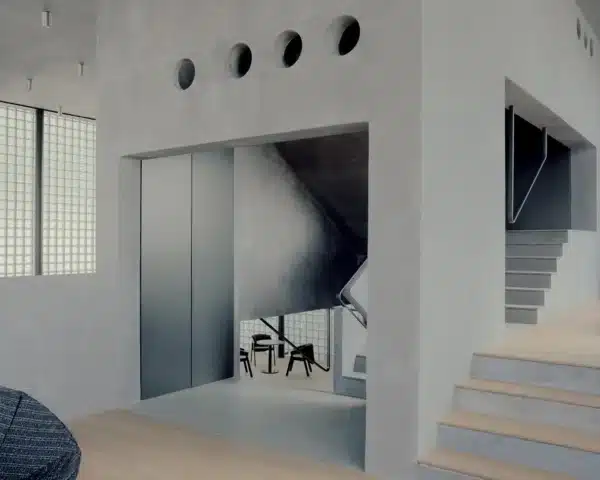 Interior view of the Wooyoungmi Manmade Flagship Store in Seoul, showing concrete walls with circular openings and a staircase leading to upper levels.