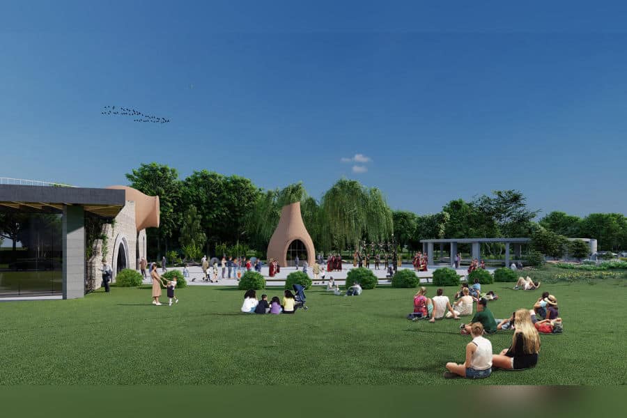 Wide-angle view of Aratta Garden&rsquo;s public lawn with visitors relaxing, children playing, and symbolic clay structures visible under a clear blue sky.
