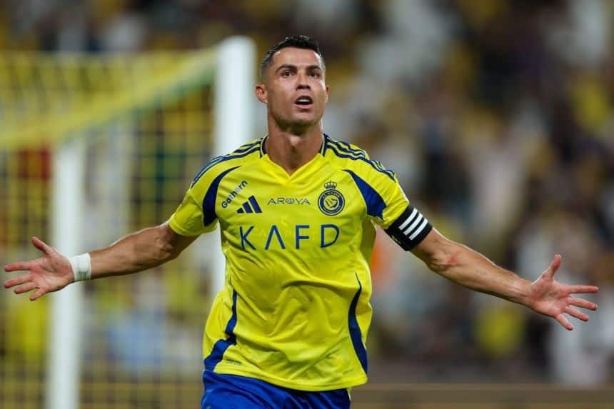 Cristiano Ronaldo in Al Nassr FC yellow and blue jersey, arms outstretched mid-action during a match under stadium lighting .Red Sea destination