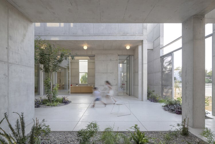 Central open courtyard surrounded by Carved Concrete masses in Nicosia house, showing two children playing and light filling the exposed concrete space.
