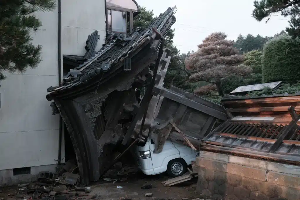 Widespread destruction resulting from the earthquake and tsunami, where wooden debris and ruined cars accumulate, illustrating the massive challenge of Seismic Resilience of Buildings for communities.