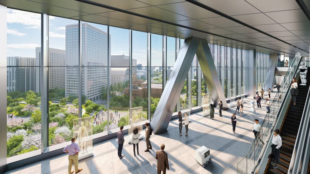 Interior view of a high-rise lobby with large windows overlooking a park and city skyline, featuring structural stabilization elements and digital displays for public engagement.