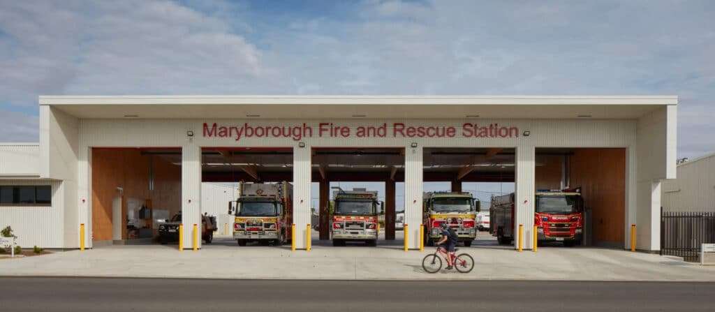 Front view of the Maryborough Fire and Rescue Station, showcasing its four bays with emergency vehicles parked under a white canopy, labeled in red lettering.