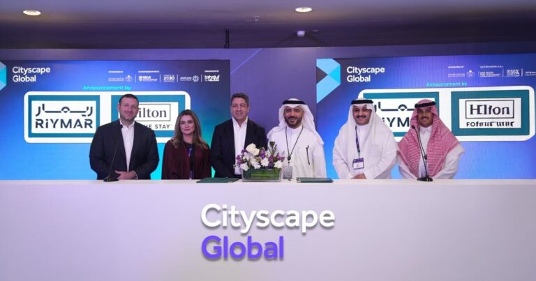 Six representatives from RiyMAR and Hilton stand behind a white podium featuring the "Cityscape Global" logo during an official announcement event.