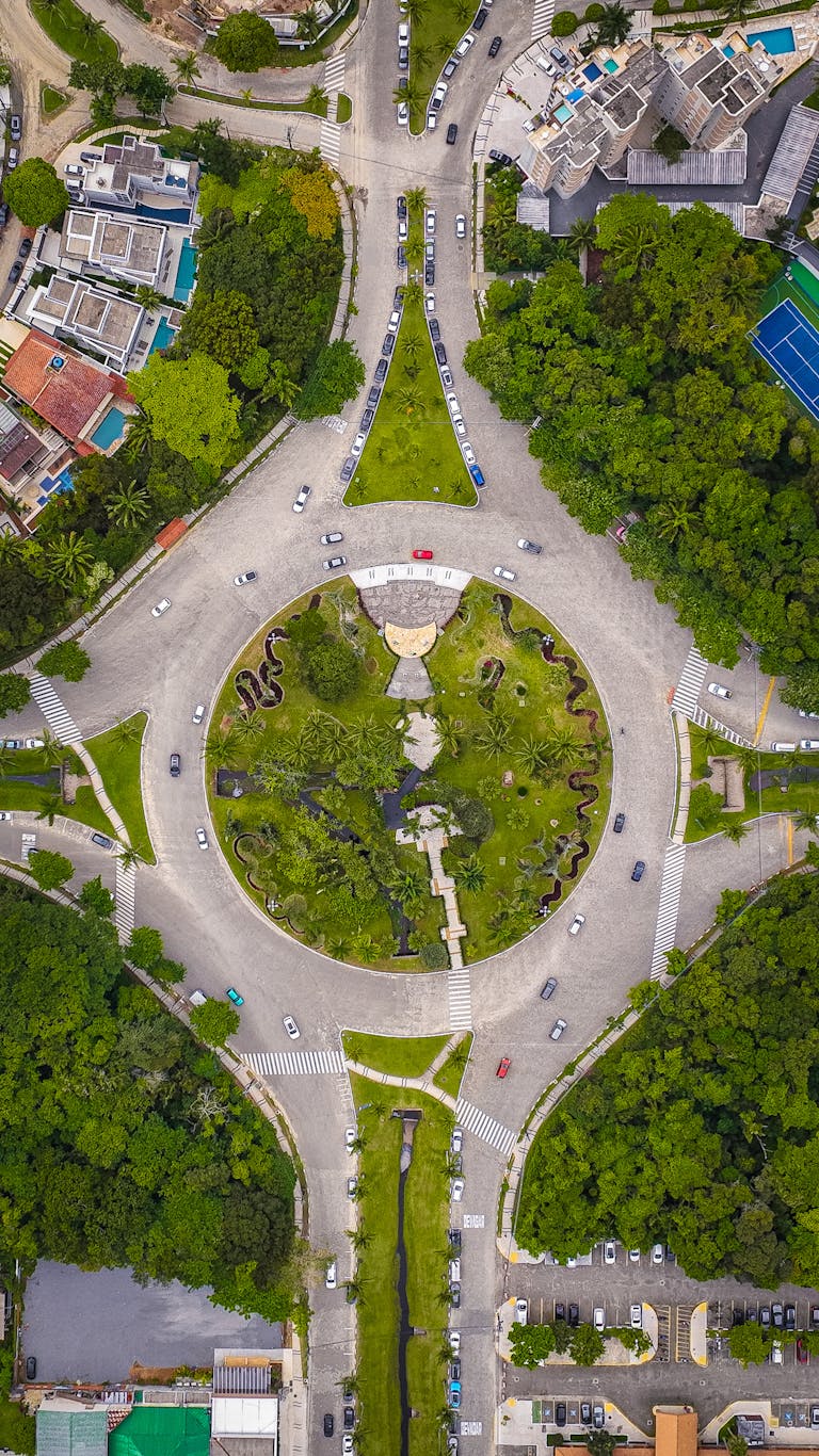 Aerial shot of a traffic roundabout surrounded by lush greenery in an urban area. Perfect for cityscape and travel themes.