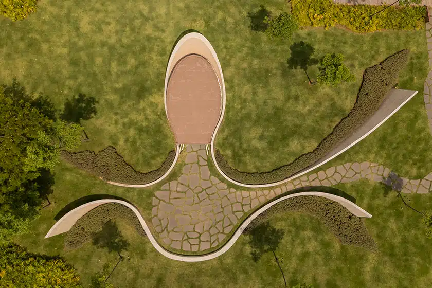 Curving exposed concrete walls encircle the oval laminated timber prayer space of the Nest Chapel in São Paulo.