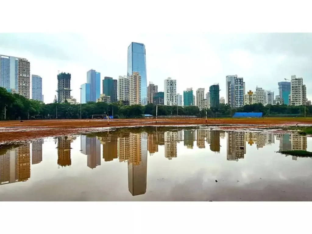 مشهد لواجهة مدينة حديثة تضم ناطحات سحاب شاهقة تنعكس بوضوح على بركة مياه بعد هطول الأمطار.