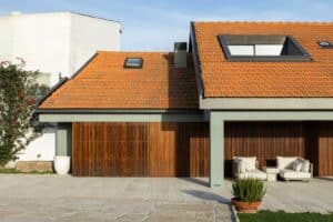 Exterior view of Casa do Engenho featuring traditional orange roof tiles, light green facade, and vertical wooden slatted sliding doors.