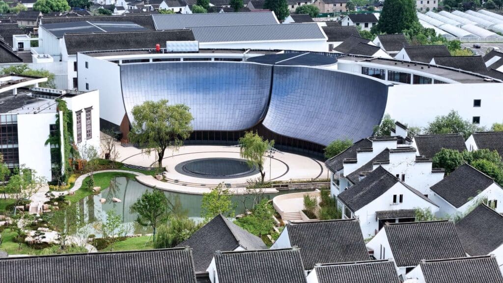 Aerial view of the Zhouzhuang theater project nestled among traditional Chinese white-walled houses with black roofs.