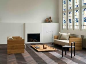 Minimalist white fireplace and wooden seating arrangement in a high-ceiling converted church interior.