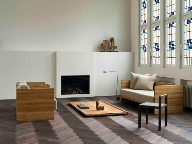 Minimalist white fireplace and wooden seating arrangement in a high-ceiling converted church interior.