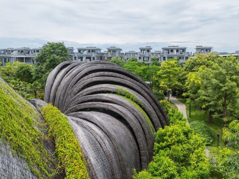 Close-up of the overlapping curved roof sections of Goot Garden House partially covered with climbing green plants.
