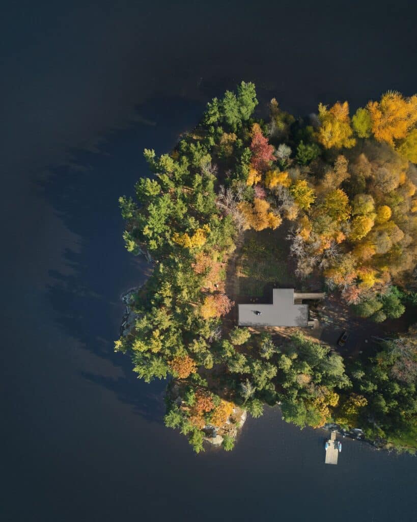 Long Lake Cabin showcases a sustainable architectural design that blends natural wood materials with the surrounding forest while offering elevated spaces and panoramic views connected seamlessly to the landscape.