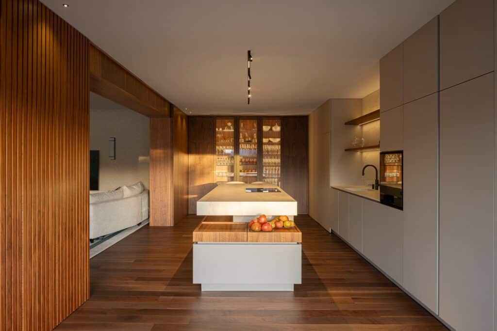 Modern kitchen design in Casa do Engenho with a white marble island, wooden cabinetry, and integrated wine cooler.