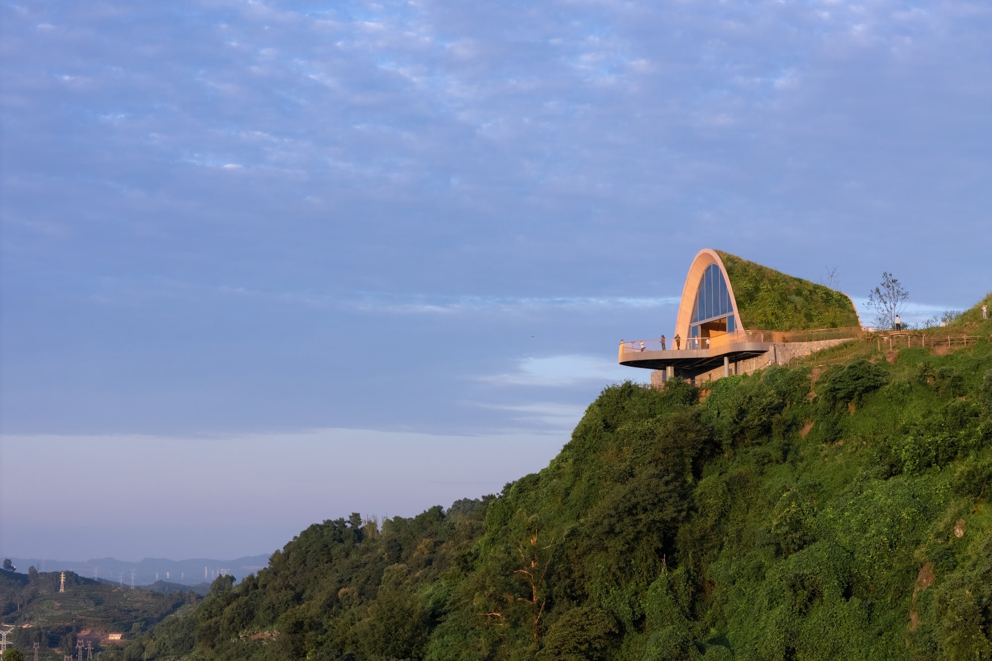 Side profile of the Pujiang Platform on a steep green hill, showing the arched structure covered in vegetation.
