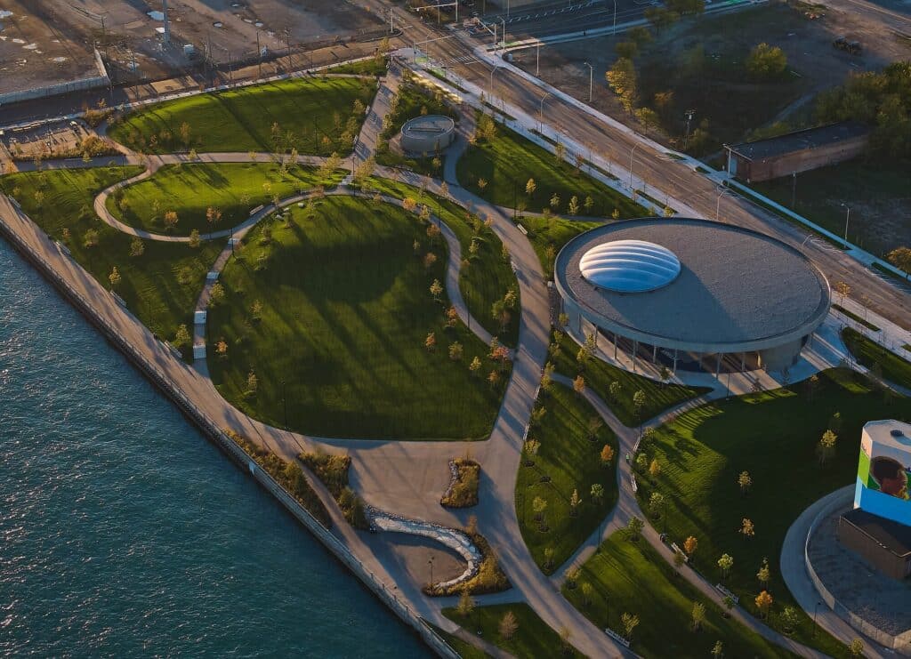 Overview of Ralph C. Wilson Jr. Centennial Park showing green spaces, pathways, and riverfront interaction in Detroit.