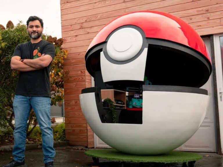 Designer Beid standing with crossed arms next to a massive, open 3D-printed Poké Ball showing internal shelves and a Bulbasaur plush.