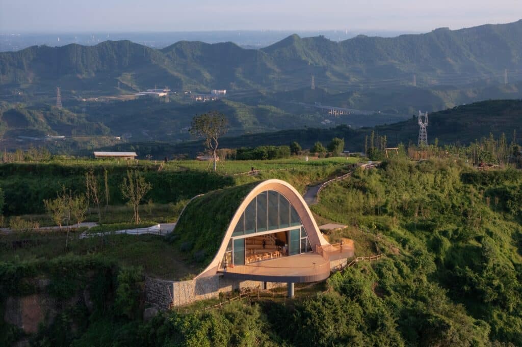 High-angle view of the Pujiang Platform showing the grass-covered arch and the semi-circular observation deck overlooking the mountains.