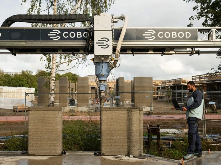 A COBOD BOD2 3D construction printer creating the concrete walls of the Skovsporet student housing project with a technician monitoring progress.