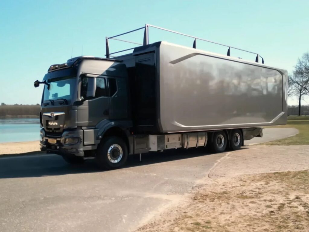 Close-up of the MAN truck chassis integrated with the Shiver x Expandable mobile living unit on a paved road.