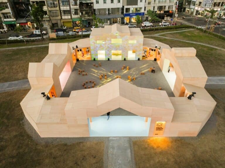 Aerial top view of the Wonders of Wood Pavilion in Chiayi, showing the rectangular wooden structure with a central gravel courtyard and glowing interior light.