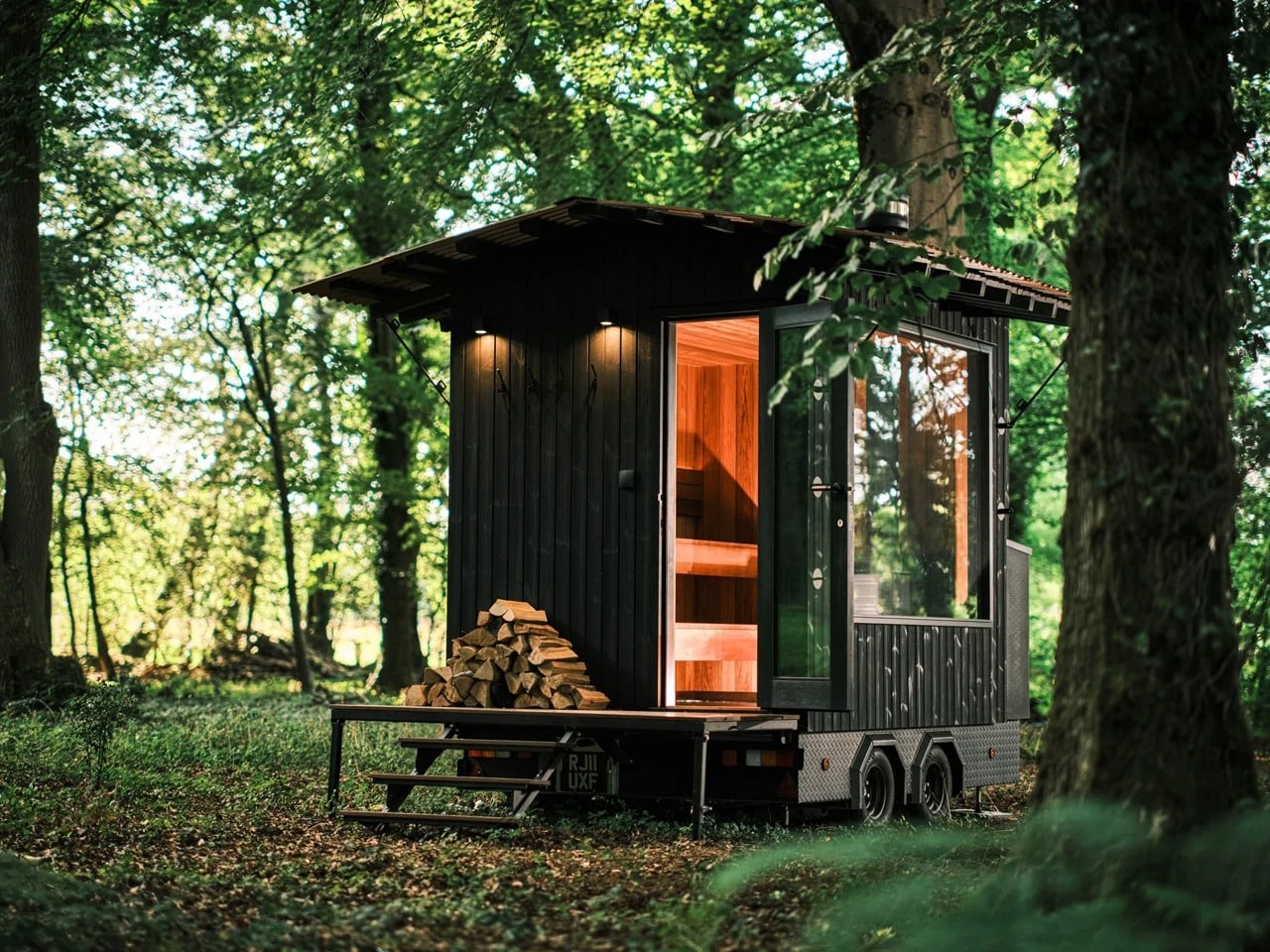 Aquila mobile sauna exterior on a dual-axle trailer showcasing black larch wood and folding roof design for remote use