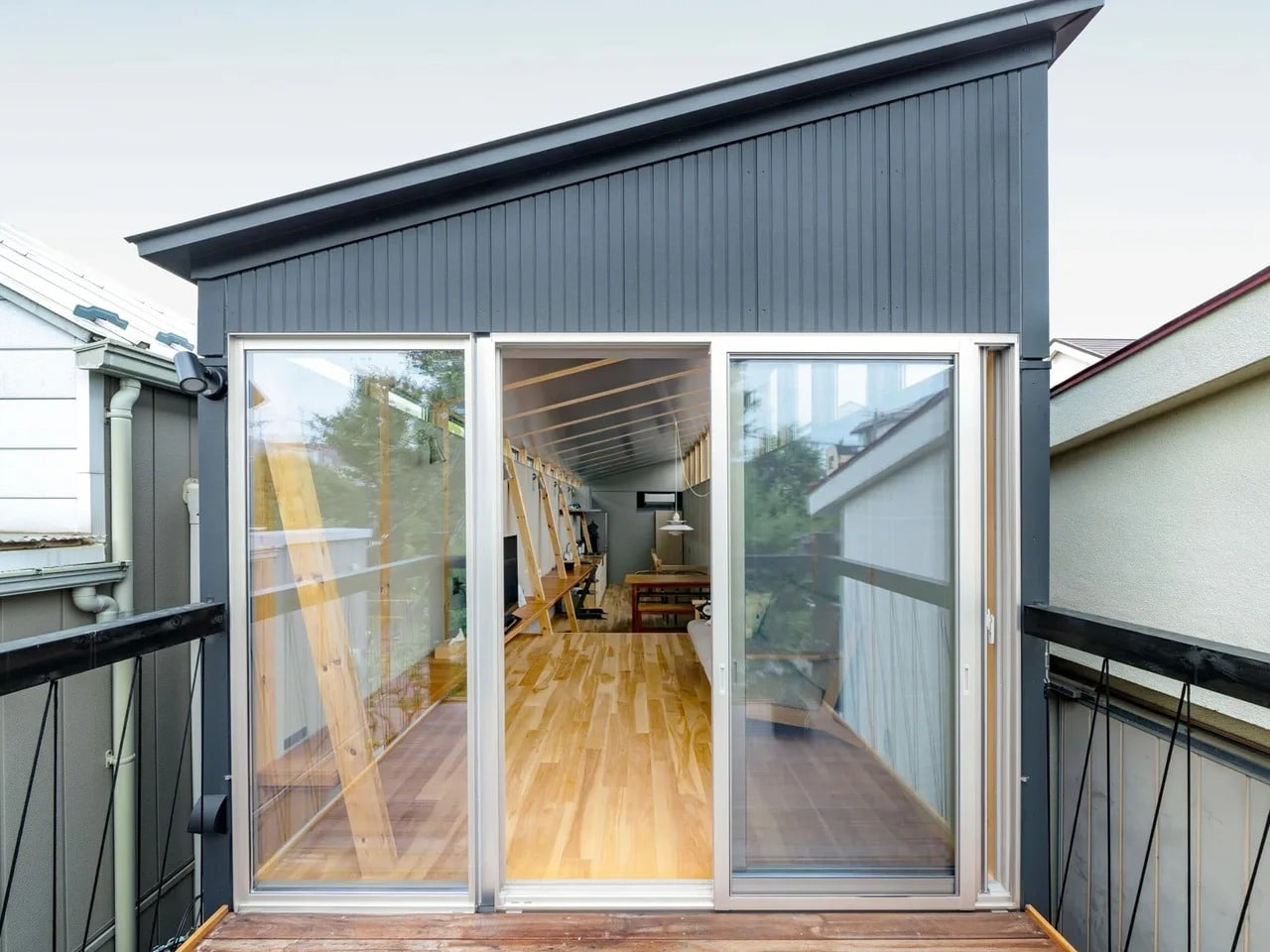 Modern narrow house in Fukasawa, Tokyo, featuring a grey corrugated metal facade and a cantilevered balcony by Taguchi Kawaguchi Architects.