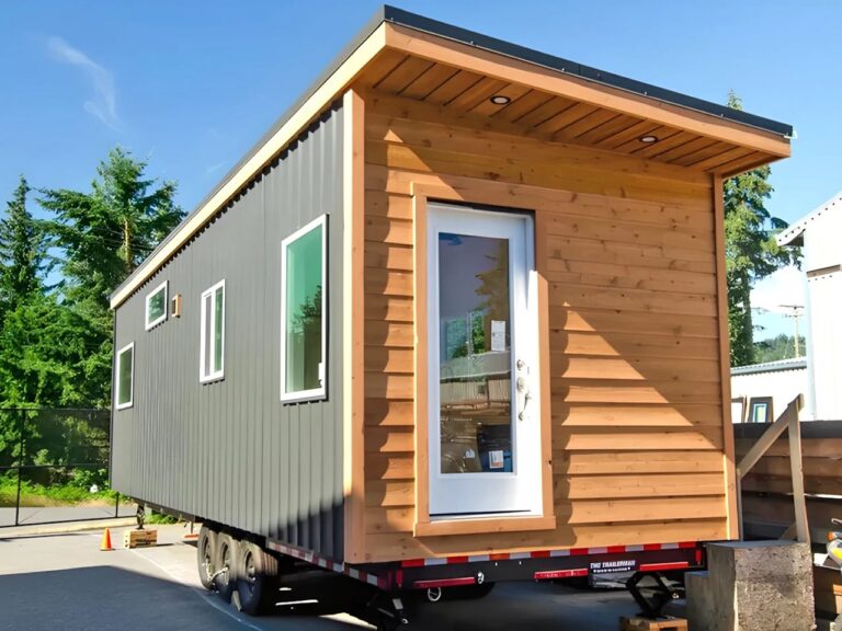 Modern tiny house exterior of Barred Owl with grey metal siding and natural wood accents on a trailer.
